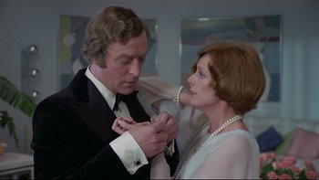 Movie still from “California Suite” (1978), directed by Herbert Ross – An older man putting a tie on a younger woman's neck; Close Up shot, Over the shoulder angle