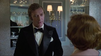Movie still from “California Suite” (1978), directed by Herbert Ross – A man in a tuxedo talking to a woman in a black suit; Medium shot, Over the shoulder angle