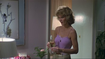 Movie still from “California Suite” (1978), directed by Herbert Ross – A woman holding a wine glass in a room; Medium shot, Over the shoulder angle