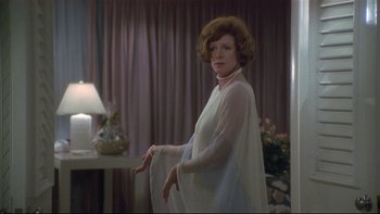 Movie still from “California Suite” (1978), directed by Herbert Ross – A woman in a white dress standing next to a lamp; Medium shot, Over the shoulder angle