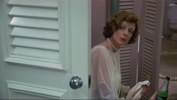 Movie still from “California Suite” (1978), directed by Herbert Ross – A woman in a white dress and pearls in a doorway; Medium shot, Over the shoulder angle