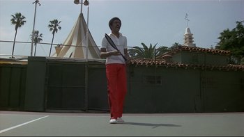 Movie still from “California Suite” (1978), directed by Herbert Ross – A woman holding a tennis racquet on top of a tennis court; Wide shot, Low angle