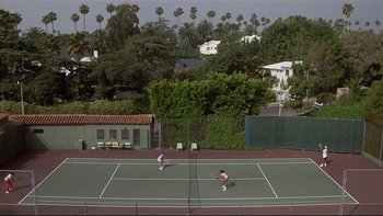 Movie still from “California Suite” (1978), directed by Herbert Ross – Two people playing tennis on a tennis court; Extreme Wide shot, High angle