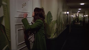 Movie still from “California Suite” (1978), directed by Herbert Ross – A woman in a green coat standing in front of a door; Wide shot, High angle