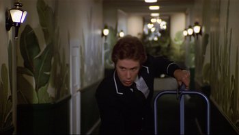 Movie still from “California Suite” (1978), directed by Herbert Ross – A man in a black jacket is holding a blue handle; Medium shot, Low angle