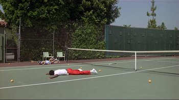Movie still from “California Suite” (1978), directed by Herbert Ross – A person laying on the ground on a tennis court; Wide shot, High angle