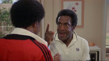 Movie still from “California Suite” (1978), directed by Herbert Ross – A man in a white shirt is talking to another man in a red and white shirt; Close Up shot, Over the shoulder angle
