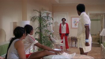 Movie still from “California Suite” (1978), directed by Herbert Ross – A group of people in a room with a plant in the background; Wide shot, Over the shoulder angle