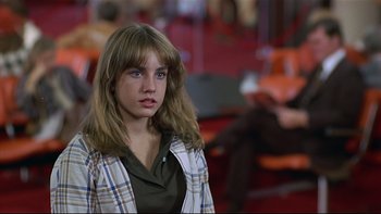 Movie still from “California Suite” (1978), directed by Herbert Ross – A young woman in a plaid shirt is looking at the camera; Close Up shot, Over the shoulder angle