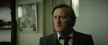 Movie still from “Calm with Horses” (2019), directed by Nick Rowland – A person wearing a suit and tie; Close Up shot, Over the shoulder angle