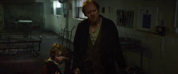 Movie still from “Calm with Horses” (2019), directed by Nick Rowland – An older man and a young boy walking in a room; Medium shot, Over the shoulder angle