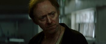 Movie still from “Calm with Horses” (2019), directed by Nick Rowland – An older man with a beard and a necklace; Close Up shot, Over the shoulder angle