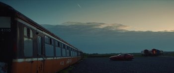 Movie still from “Calm with Horses” (2019), directed by Nick Rowland – A car parked next to a train on the side of the road; Extreme Wide shot, Low angle
