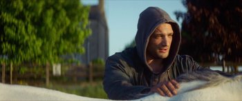 Movie still from “Calm with Horses” (2019), directed by Nick Rowland – A man in a hooded jacket is leaning against a wall; Medium shot, Low angle