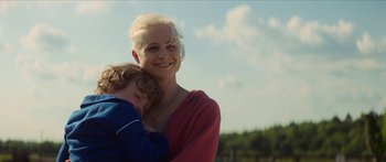 Movie still from “Calm with Horses” (2019), directed by Nick Rowland – A woman and a child are smiling for the camera; Close Up shot, Low angle