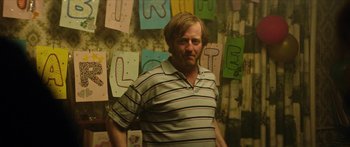 Movie still from “Calm with Horses” (2019), directed by Nick Rowland – A man standing in front of a wall with letters on it; Medium shot, Over the shoulder angle