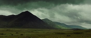 Movie still from “Calm with Horses” (2019), directed by Nick Rowland – A mountain range under a cloudy dark sky; Extreme Wide shot, Low angle