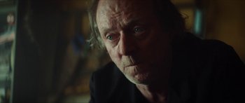 Movie still from “Calm with Horses” (2019), directed by Nick Rowland – An old man with a beard and a black shirt is looking at the camera; Close Up shot, Over the shoulder angle