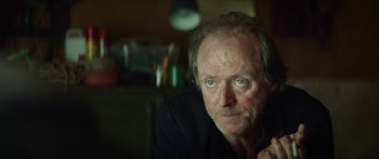 Movie still from “Calm with Horses” (2019), directed by Nick Rowland – An older man with blue eyes sitting in front of a lamp; Close Up shot, Over the shoulder angle