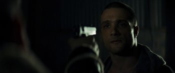 Movie still from “Calm with Horses” (2019), directed by Nick Rowland – A person holding a gun in a dark room; Close Up shot, Over the shoulder angle