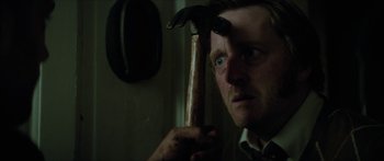 Movie still from “Calm with Horses” (2019), directed by Nick Rowland – A man holding a hammer in a dark room; Close Up shot, Low angle