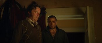 Movie still from “Calm with Horses” (2019), directed by Nick Rowland – Two men standing next to each other in the dark; Medium shot, Low angle