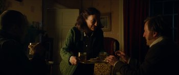 Movie still from “Calm with Horses” (2019), directed by Nick Rowland – An older woman holding a tray of food and a glass; Medium shot, Over the shoulder angle