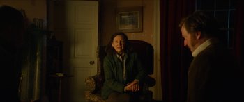 Movie still from “Calm with Horses” (2019), directed by Nick Rowland – An older woman sitting in a chair in a living room; Medium shot, Over the shoulder angle