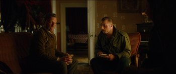 Movie still from “Calm with Horses” (2019), directed by Nick Rowland – A couple of men sitting next to each other in a room; Medium shot, Over the shoulder angle