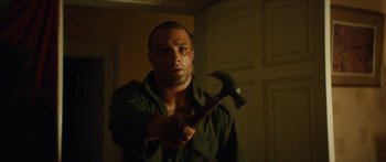 Movie still from “Calm with Horses” (2019), directed by Nick Rowland – A man holding a hammer in a room; Close Up shot, Low angle