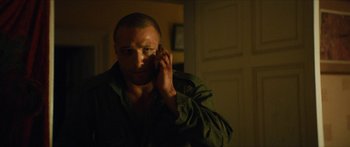 Movie still from “Calm with Horses” (2019), directed by Nick Rowland – A man is talking on a cell phone in the dark; Close Up shot, Over the shoulder angle