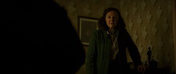 Movie still from “Calm with Horses” (2019), directed by Nick Rowland – An older woman standing in front of a mirror in a dark room; Medium shot, Over the shoulder angle