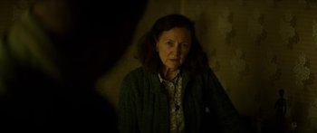 Movie still from “Calm with Horses” (2019), directed by Nick Rowland – An older woman is standing in a dark room; Close Up shot, Over the shoulder angle