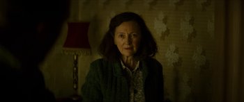 Movie still from “Calm with Horses” (2019), directed by Nick Rowland – An older woman is standing in a dark room; Close Up shot, High angle