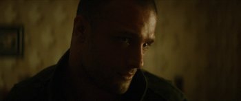 Movie still from “Calm with Horses” (2019), directed by Nick Rowland – A man's face in a dimly - lit room; Close Up shot, Over the shoulder angle