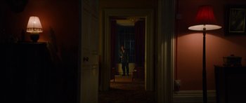 Movie still from “Calm with Horses” (2019), directed by Nick Rowland – A man standing in a dark room in front of a window; Wide shot, Low angle