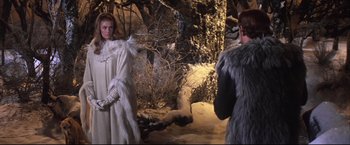 Movie still from “Camelot” (1967), directed by Joshua Logan – Two people dressed in white and fur standing next to each other in a forest; Medium shot, Over the shoulder angle