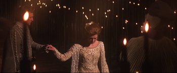 Movie still from “Camelot” (1967), directed by Joshua Logan – A woman in a white dress standing in front of a bunch of lights; Medium shot, Low angle