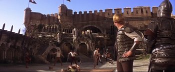 Movie still from “Camelot” (1967), directed by Joshua Logan – A group of people in medieval garb in front of a castle; Extreme Wide shot, Low angle