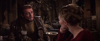 Movie still from “Camelot” (1967), directed by Joshua Logan – A man and a woman sitting at a table talking to each other; Medium shot, Over the shoulder angle