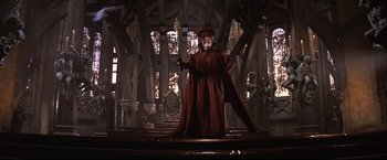 Movie still from “Camelot” (1967), directed by Joshua Logan – A man dressed as a wizard holding a staff; Wide shot, Low angle