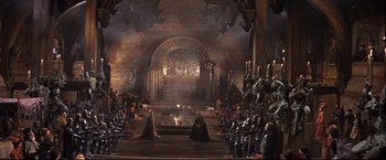 Movie still from “Camelot” (1967), directed by Joshua Logan – A group of people sitting around a fire in a room; Extreme Wide shot, High angle