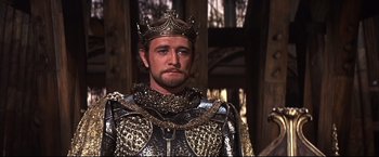 Movie still from “Camelot” (1967), directed by Joshua Logan – A person wearing a crown and armor; Close Up shot, High angle
