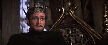 Movie still from “Camelot” (1967), directed by Joshua Logan – A person wearing a crown near a chair; Close Up shot, Low angle