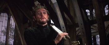 Movie still from “Camelot” (1967), directed by Joshua Logan – A man wearing a crown and holding a roll of paper; Close Up shot, Low angle