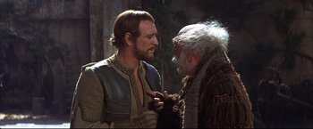 Movie still from “Camelot” (1967), directed by Joshua Logan – A man and an old man talking to each other; Medium shot, Over the shoulder angle