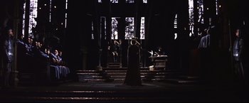 Movie still from “Camelot” (1967), directed by Joshua Logan – A woman standing in front of two men in front of a window; Wide shot, High angle