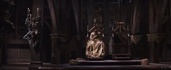 Movie still from “Camelot” (1967), directed by Joshua Logan – A woman sitting on a throne in a room; Wide shot, High angle