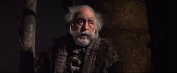 Movie still from “Camelot” (1967), directed by Joshua Logan – An old man with long white hair and a beard; Medium shot, Low angle