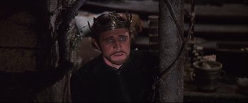 Movie still from “Camelot” (1967), directed by Joshua Logan – A man wearing a gold crown standing next to a tree; Close Up shot, High angle